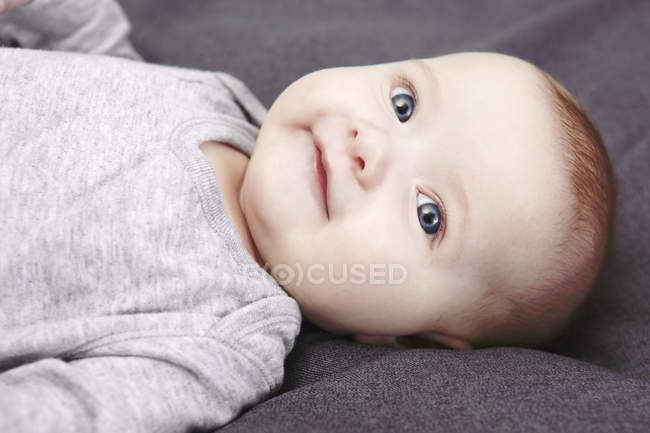 Portrait studio de bébé fille souriante couchée sur le dos — Photo de stock