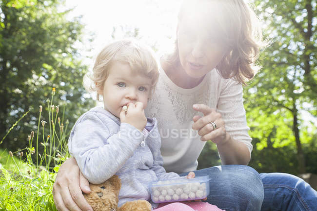 Mutter und Kleinkind essen Süßigkeiten im Park — Stockfoto