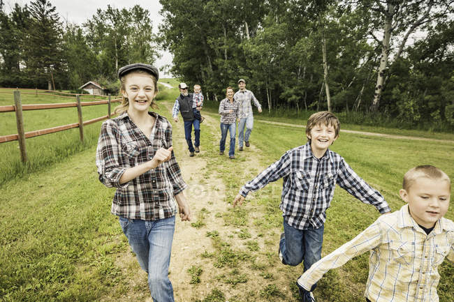 Front view of children running on dirt track looking at camera smiling — Stock Photo