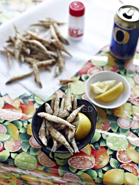 Many whitebait in bowl with lemon salt and beer can — Stock Photo