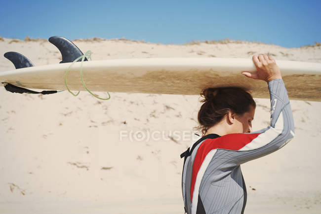 Surfeur portant une planche de surf sur la tête à la plage, Lacanau, France — Photo de stock