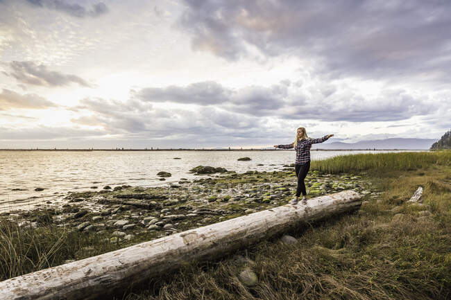 Frau balanciert auf Baumstamm am Wrack Beach, Vancouver, Kanada — Stockfoto