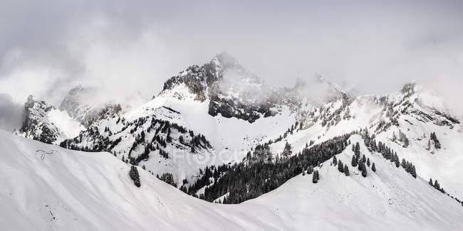 Neve coberto paisagem montanhosa com nuvens baixas — Fotografia de Stock