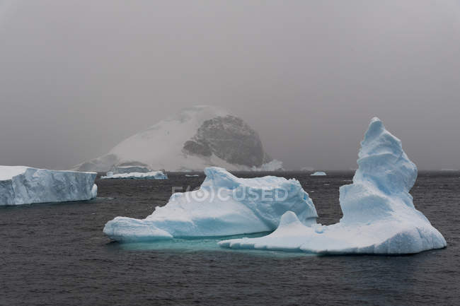 Nubes bajas sobre icebergs en el canal Lemaire, Antártida - foto de stock