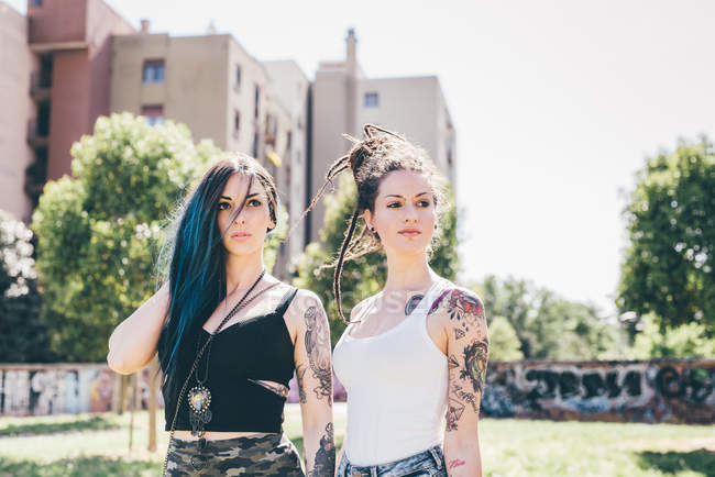 Dos mujeres jóvenes mirando de lado en el parque urbano - foto de stock