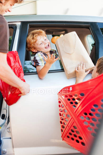 Pai e filhos carregando mantimentos em carro — Fotografia de Stock