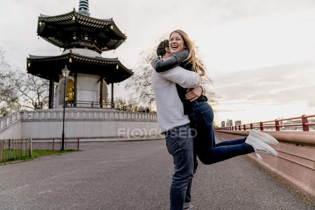 Felice giovane uomo abbracciare fidanzata a Battersea Park, Londra, Regno Unito — Foto stock