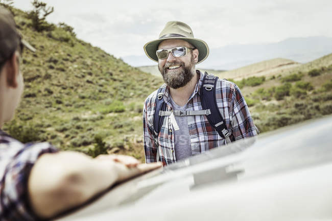 Man and teenage son on hiking road trip leaning on car roof in landscape, Bridger, Montana, USA — Stock Photo