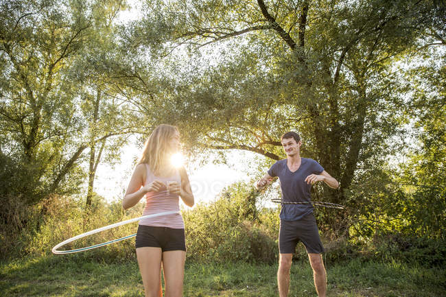 Young couple in rural environment, using hula hoops — Stock Photo