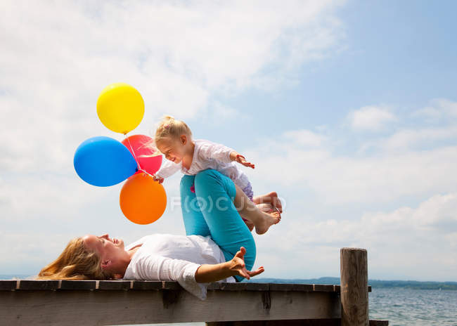 Mother and daughter playing on pier — Stock Photo
