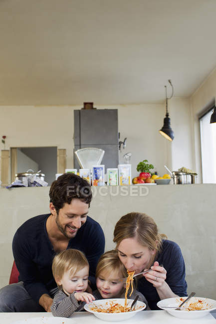 Familia con dos hijas comiendo espaguetis - foto de stock