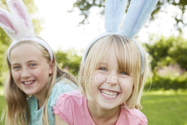 Retrato de dos niñas en tocado de plumas en el jardín - foto de stock