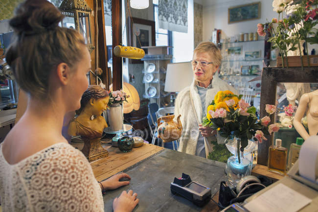 Madura cliente femenino comprar tetera en tienda vintage - foto de stock