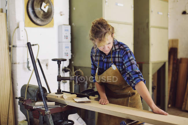 Young craftswoman checking wood in pipe organ workshop — Stock Photo
