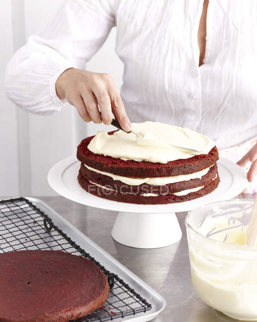 Cropped image of woman making chocolate cake with cream — Stock Photo