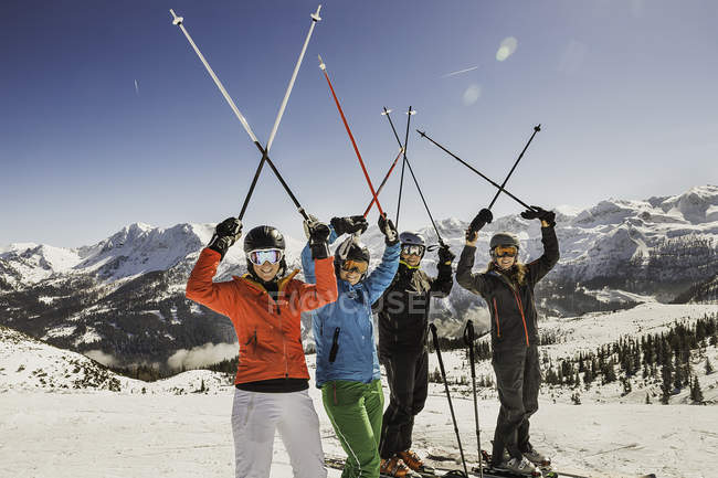 Portrait of skiers on slope, holding ski poles in the air — Stock Photo