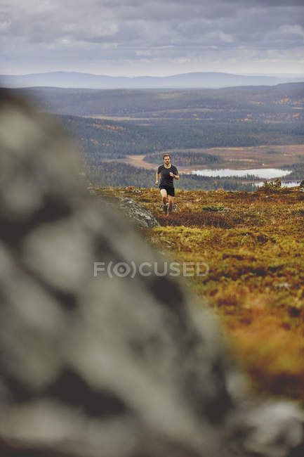 Man trail running on rocky cliff top, Keimiotunturi, Lapland, Finlândia — Fotografia de Stock