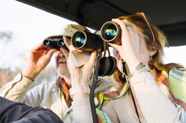 Senior man and daughter looking out through binoculars on safari, Kafue National Park, Zambia — Stock Photo