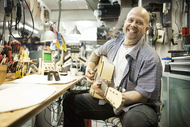Portrait des Gitarristen beim Stimmen der akustischen Gitarre in der Werkstatt — Stockfoto