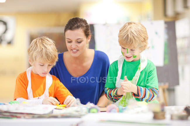 Joven mujer y niños en clase de arte - foto de stock