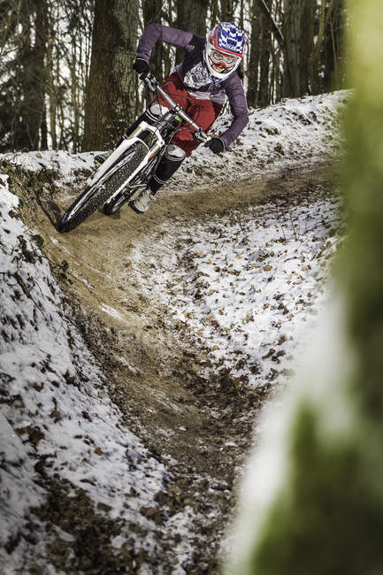 Young female mountain biker riding a forest dirt track — Stock Photo