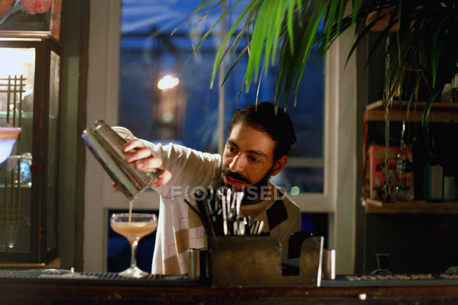 Cantinero macho sirviendo cóctel en el bar - foto de stock