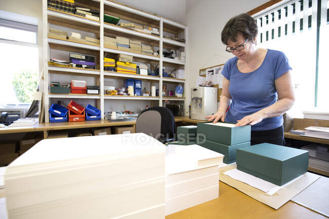 Ordine di imballaggio operaio femminile in scatola di cartone in officina di stampa — Foto stock