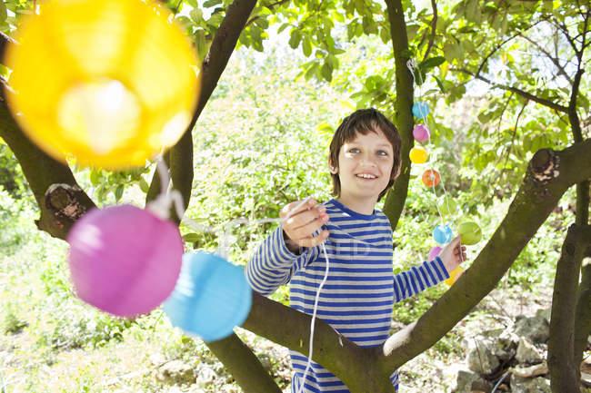 Menino colocando luzes de fadas na árvore — Fotografia de Stock