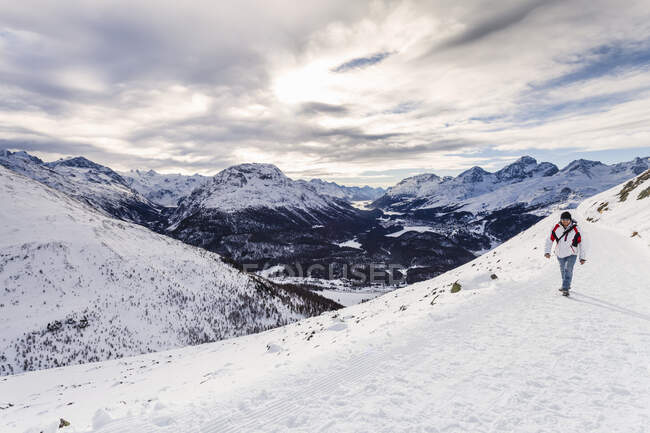 Чоловік, що ходить по снігу, покриває гори, задній вид, Енгадін, Швейцарія. — стокове фото