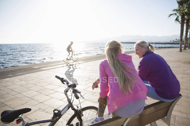 Two blonde women relaxing by beach in backlit — Stock Photo