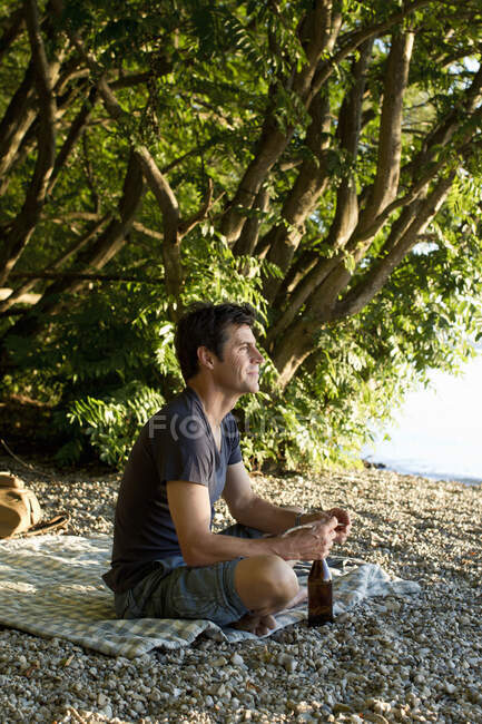 Зрелый мужчина отдыхает на берегу озера — стоковое фото