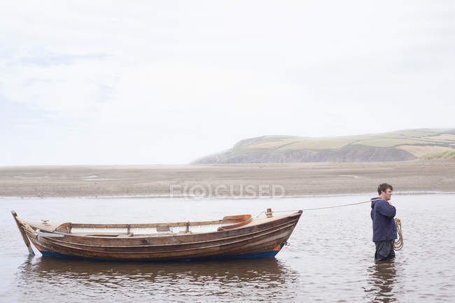 Человек тянет лодку через воду — стоковое фото