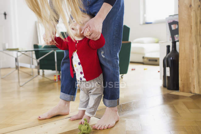 Niña sosteniendo las manos de las madres para dar los primeros pasos - foto de stock