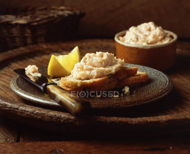 Рибний паштет на нарізаному хлібі з лимонним шматочком — стокове фото