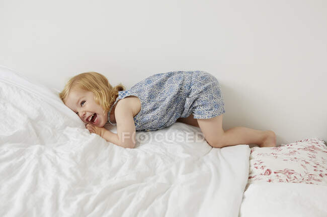 Niedliche weibliche Kleinkind spielen auf Bett — Stockfoto