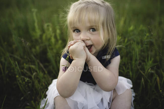 Retrato de menina sentada na grama olhando para a câmera — Fotografia de Stock