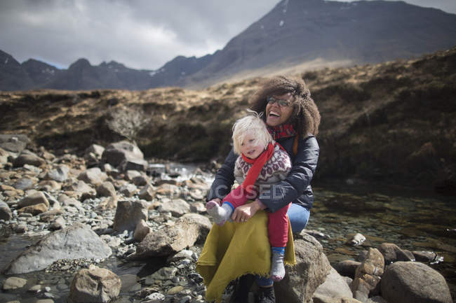 Mãe e filho sentados em rochas, Fairy Pools, Ilha de Skye, Hébridas, Escócia — Fotografia de Stock