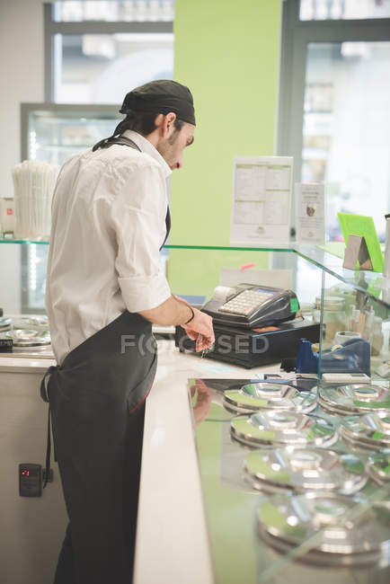 Camarero masculino usando caja registradora en la cafetería - foto de stock