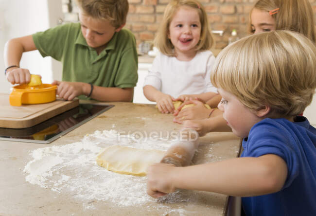 Quatro miúdos que cozem bolinhos — Fotografia de Stock