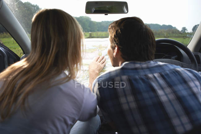 Couple of travelers in car map reading preparing for adventure, rear view — Stock Photo