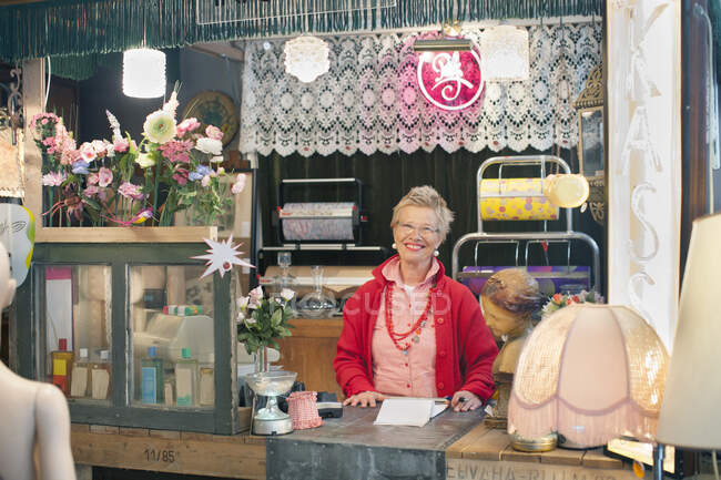 Portrait of mature woman behind vintage shop counter — Stock Photo