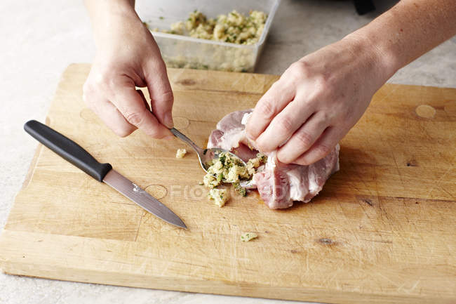 Mani delle donne ripieno bistecche di maiale sul tagliere — Foto stock