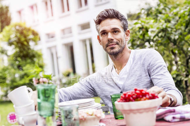 Hombre adulto medio sentado a la mesa en el jardín - foto de stock