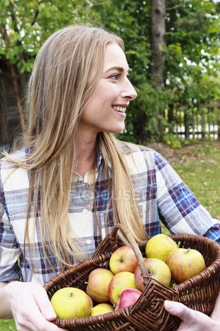 Mulher adulta média segurando cesta de maçãs domésticas — Fotografia de Stock