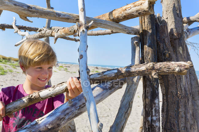 Boy making driftwood shelter, Caleri Beach, Veneto, Italia - foto de stock