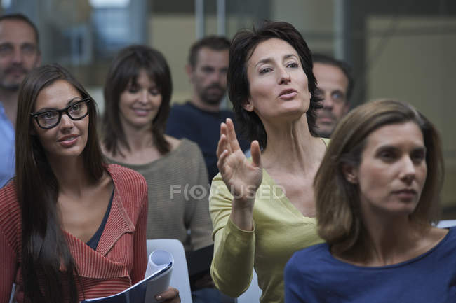 Grupo assistindo apresentação, mulher madura levantando a mão — Fotografia de Stock