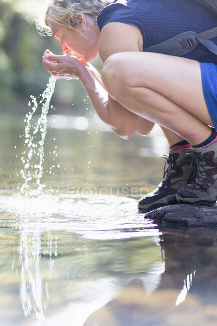 Hiker washing face with water from shallow stream — Stock Photo