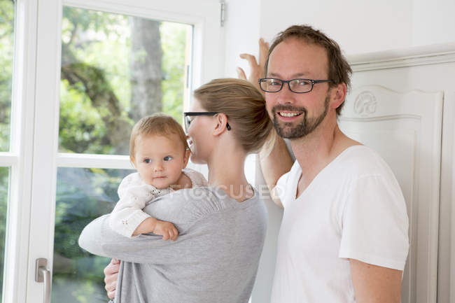 Mutter und Vater blicken mit kleiner Tochter aus dem Fenster — Stockfoto