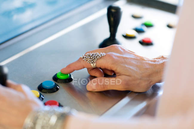 Fechar o botão de pressão da mão da mulher sênior na máquina de jogos — Fotografia de Stock