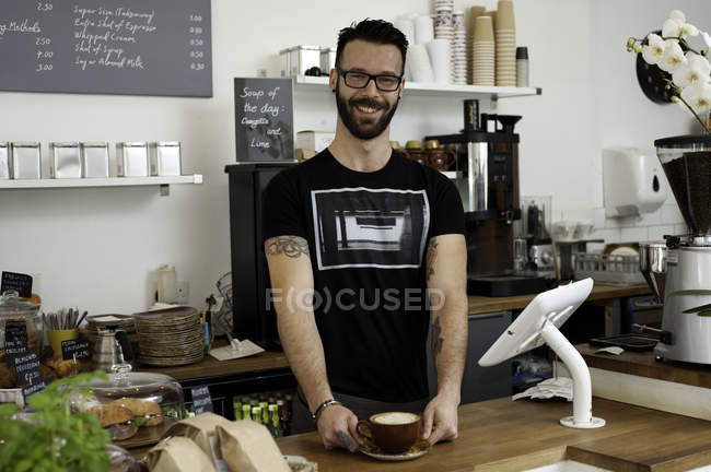 Portrait of cafe waiter serving coffee from counter — Stock Photo